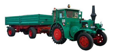 Freigestellter grüner Lanz-Bulldog-Traktor des Fuhrbetriebs Hilbert mit geschlossener Fahrerkabine und zweiachsigem, grün-rotem Kippanhänger.